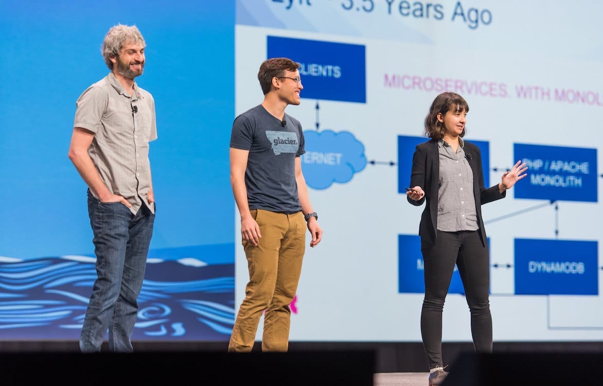 A woman and two men presenting technical info on a stage